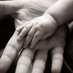 Liten barnhand vilar i en vuxens hand