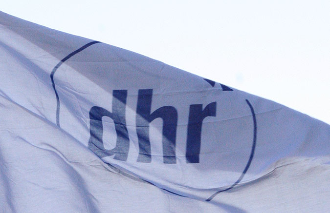 En vit flagga med den blå DHR-loggan.