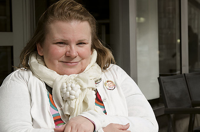 Maia Joahnsson sitter vid bord i vit kofta och halsduk.
