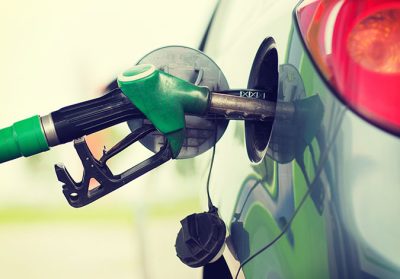 Ett tankhantag på en bensinstation sitter instucket i en grön bil.