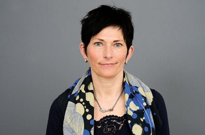 Porträttfoto av en kvinna mot grå bakgrund.