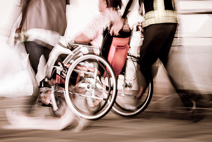 En oskarp bild på en person i rullstol som blir körd av en annan person.