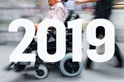 En suddigbild av en man i rullstol med årtalet 2019 skrivet över.