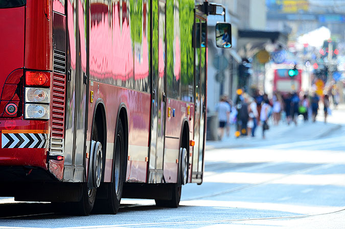 En röd buss kör på gata i stan.