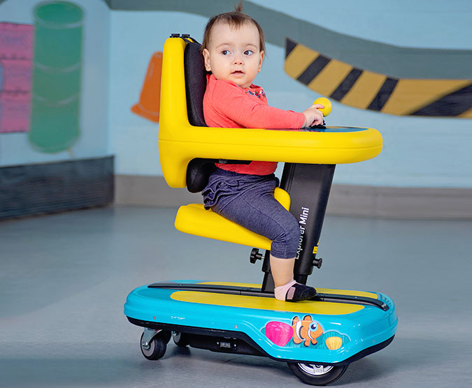 Litet barn sitter i en gul plaststol som går på hjul.