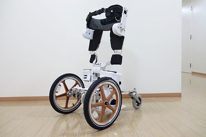 Bild på Quolo som ser ut som ett exoskelett som står på en plattform med två stora hjul fram och två små bak