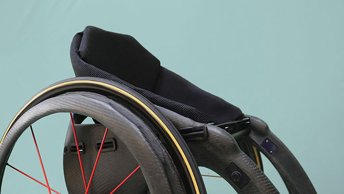En svart rullstol där ekrarna i hjulet är röda.