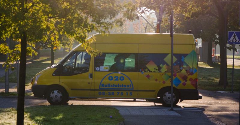 En färdtjänstbuss kör i bland grönskande träd