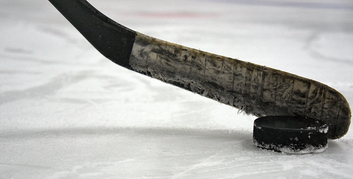 Bladet på en hockeyklubba och en puck på is.