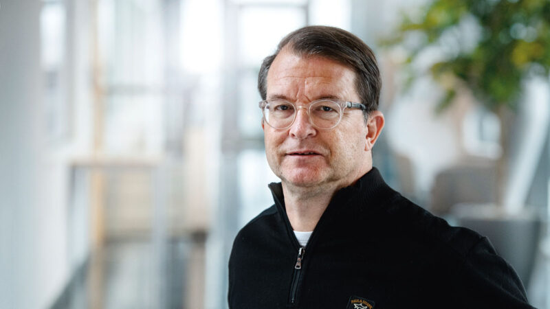 Portätt av man i snedlugg och runda glasögon.