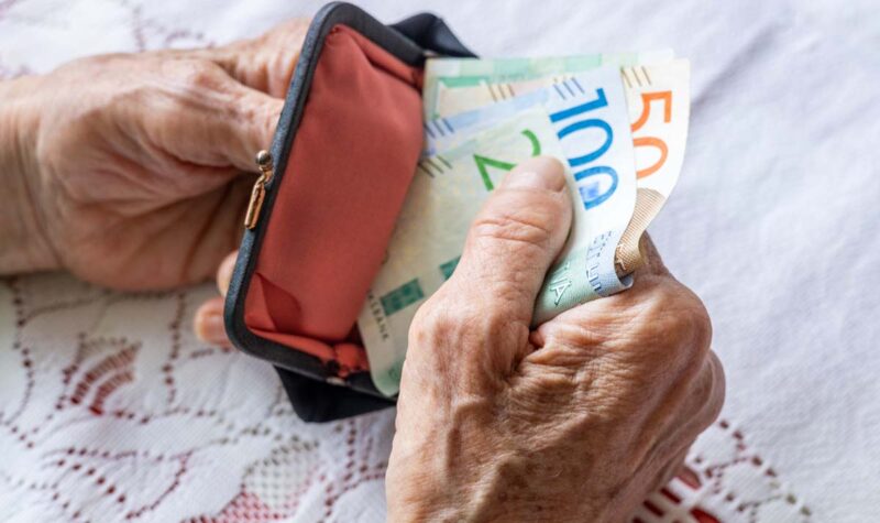 Två händer som håller i en plånbok med några sedlar av mindre valör.