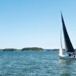 En segelbåt på vatten med gröna öar i bakgrunden.