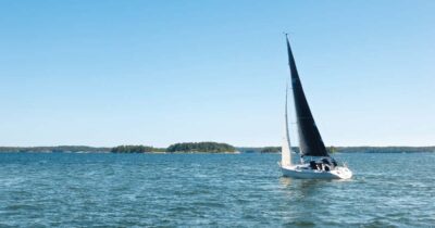 En segelbåt på vatten med gröna öar i bakgrunden.