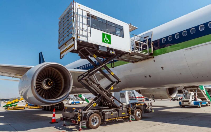 En lift fö personer med nedsatt rörelseförmåga står i uppfällt läge bredvid ett flygplan pop en flygplats.