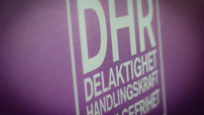 En suddig bild av DHR:s logotyp på en lila bakgrund. Foto: Albert Martinsson