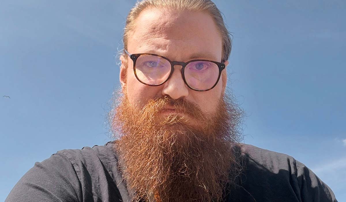 Porträttbild av en man med skägg och glasögon.